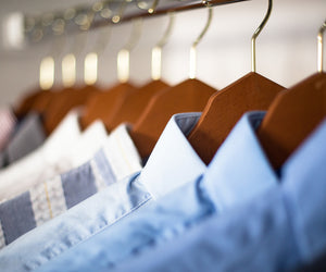 Row of blue shirts on wooden hangers with blurred lights in the background