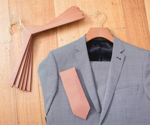 Gray suit jacket with a pink tie on a wooden floor