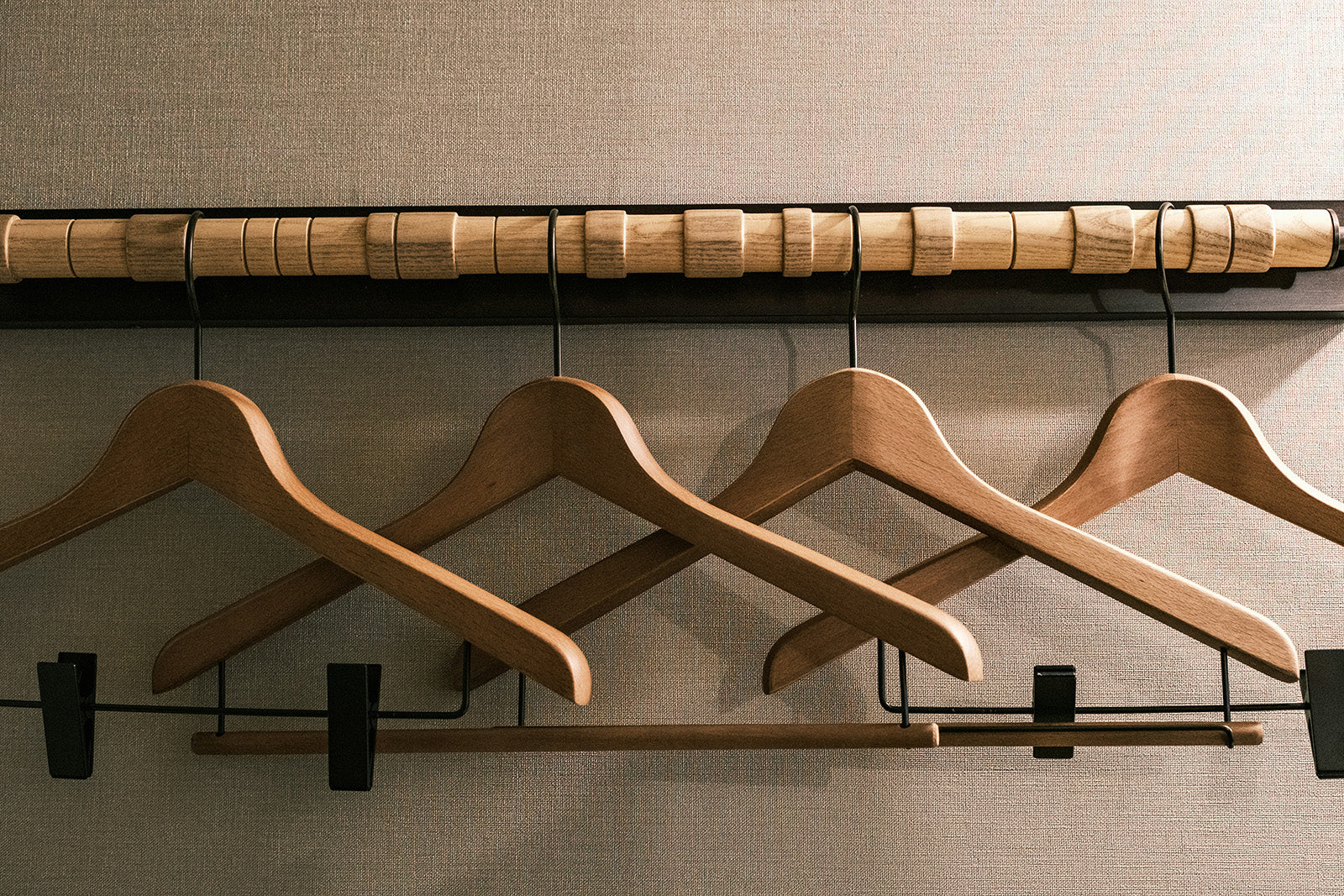 Wooden hangers on a rack against a neutral wall
